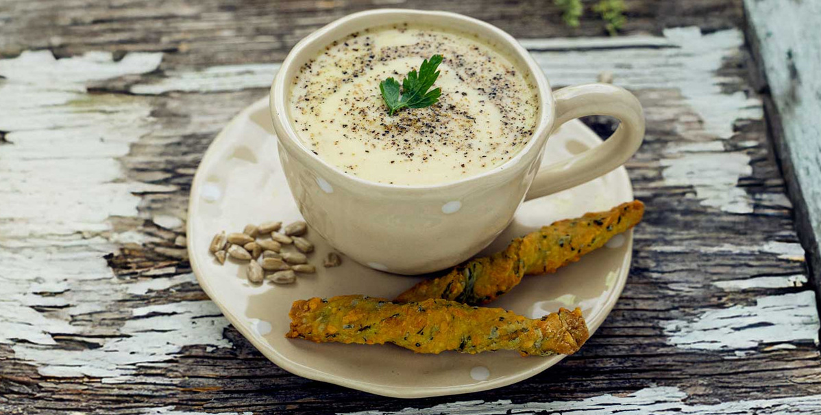 KI generiert: Das Bild zeigt eine Schüssel mit einem bunten Salat aus Rote-Bete-Scheiben, Karottenstreifen, Feldsalat, gehackten Nüssen und einem Klecks Sahne oder Joghurt in der Mitte. Der Salat liegt auf einem Holztisch.