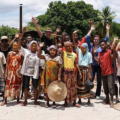 KI generiert: Eine Gruppe von Menschen posiert lächelnd und winkend für ein Foto im Freien.