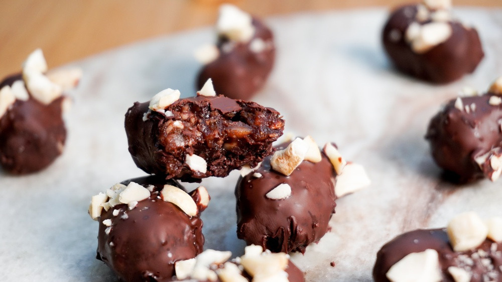 KI generiert: Das Bild zeigt eine Schüssel mit einem bunten Salat aus Rote-Bete-Scheiben, Karottenstreifen, Feldsalat, gehackten Nüssen und einem Klecks Sahne oder Joghurt in der Mitte. Der Salat liegt auf einem Holztisch.