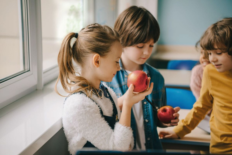 KI generiert: Kinder in einem Klassenzimmer halten Äpfel in der Hand.