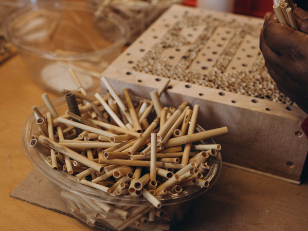 KI generiert: Ein Behälter voller Bambusröhrchen neben einem Brett mit Lochmuster.