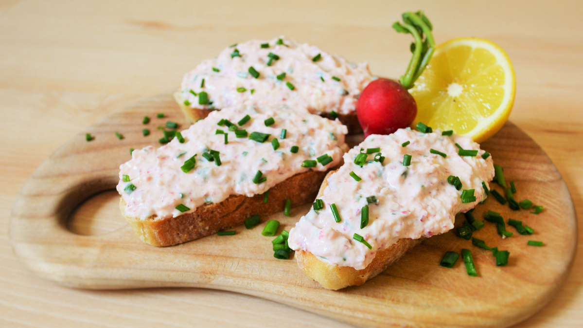 KI generiert: Das Bild zeigt eine Schüssel mit einem bunten Salat aus Rote-Bete-Scheiben, Karottenstreifen, Feldsalat, gehackten Nüssen und einem Klecks Sahne oder Joghurt in der Mitte. Der Salat liegt auf einem Holztisch.