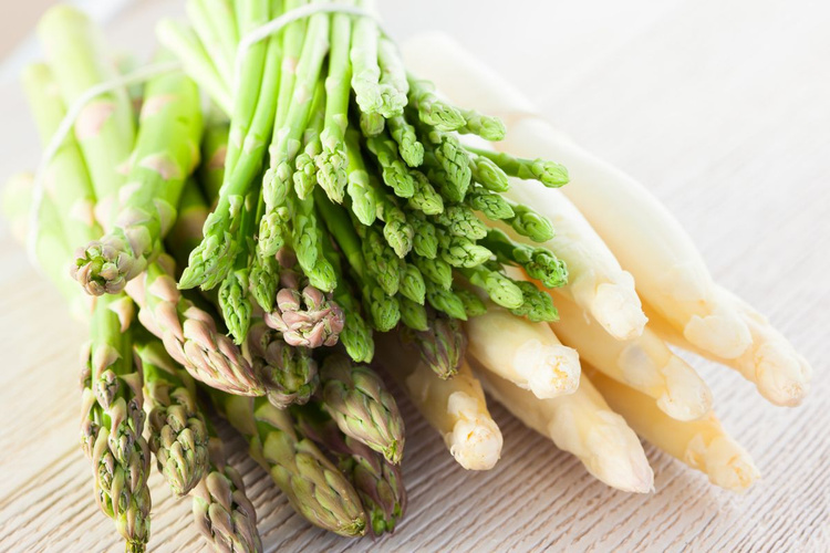 KI generiert: Verschiedene Bündel grüner und weißer Spargel auf einem hellen Hintergrund.