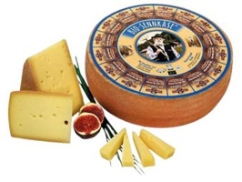 KI generiert: Ein großer Laib Bio-Sennkäse mit geschnittenem Käse und Feigen.