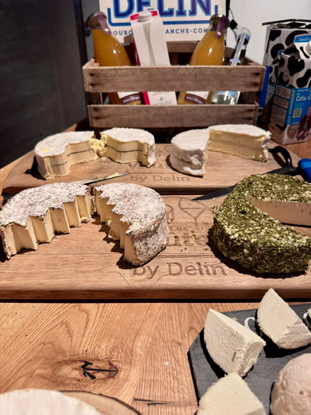 KI generiert: Käseplatten mit verschiedenen Sorten; im Hintergrund stehen Flaschen und Verpackungen.