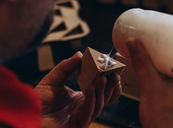 KI generiert: Eine Person trägt Kleber auf ein kleines Holzstück auf.