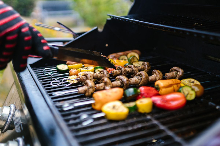 KI generiert: Gemüse und Pilze beim Grillen auf einem Grill mit einer Zange gedreht.