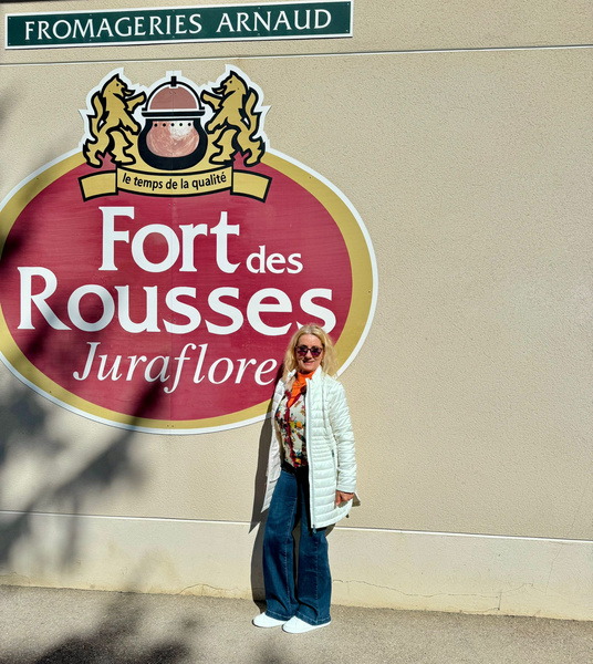 KI generiert: Eine Person steht vor einem großen Schild mit der Aufschrift "Fort des Rousses, Juraflore".