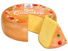 KI generiert: Ein runder Laib Käse mit Stück herausgeschnitten. Etikett oben drauf.