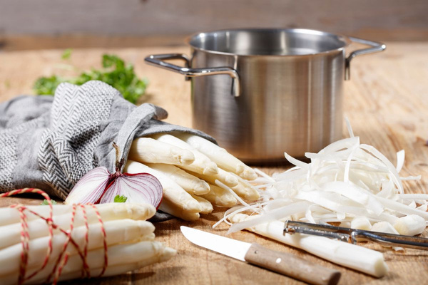 KI generiert: Das Bild zeigt zwei Personen in grüner Arbeitskleidung, die lächelnd eine Kiste mit frischem Obst und Gemüse halten. Im Hintergrund sind weitere Kisten mit Tomaten, Äpfeln und Salat zu sehen, was auf ein Lager oder eine Verkaufsstelle für frische Lebensmittel hinweist.