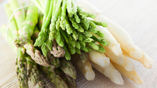 KI generiert: Ein Bündel grüner und weißer Spargel auf einem Holztisch.