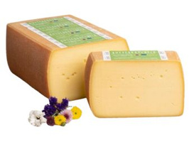 KI generiert: Ein runder Laib Käse, teils aufgeschnitten. Auf der Rinde: "Almradler Bio-Heumilchkäse".