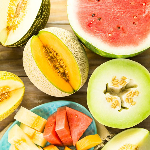 KI generiert: Verschiedene halbierte Melonensorten und geschnittene Fruchtstücke auf einem Tisch arrangiert.