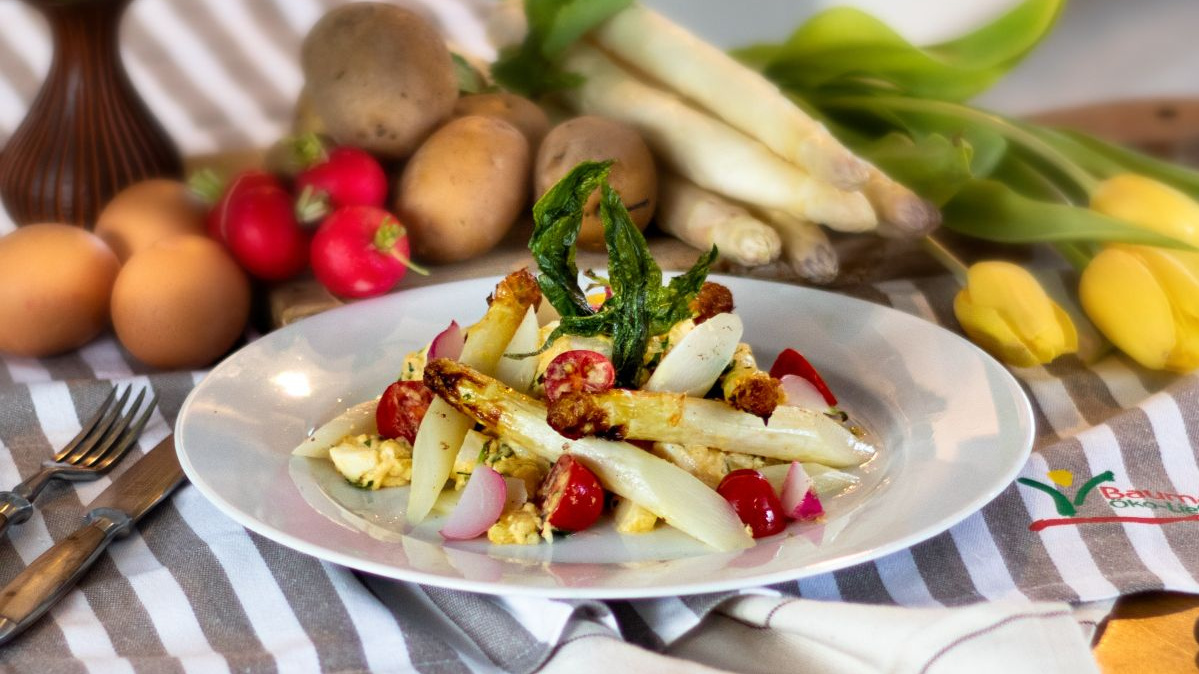 KI generiert: Das Bild zeigt eine Schüssel mit einem bunten Salat aus Rote-Bete-Scheiben, Karottenstreifen, Feldsalat, gehackten Nüssen und einem Klecks Sahne oder Joghurt in der Mitte. Der Salat liegt auf einem Holztisch.