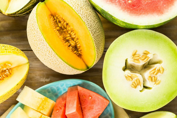 KI generiert: Das Bild zeigt ein hölzernes Brett mit einer Auswahl an verschiedenen Käsesorten, Trauben, Nüssen und Baguettescheiben. Daneben stehen zwei Weingläser, eines davon mit Rotwein gefüllt.