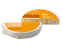 KI generiert: Käse im Anschnitt mit orange-weißer Verpackung. Text: "WEISSER KÜRBISKERNBEISSER" und "EIN SONNENAUFGANG WIE DER HONIG."

