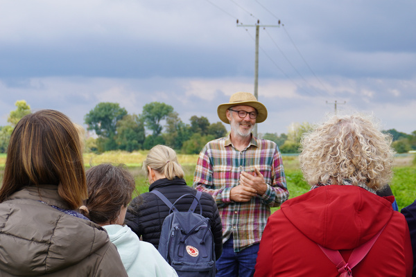 KI generiert: Eine Gruppe von Menschen lauscht einem Mann auf einem Feld.