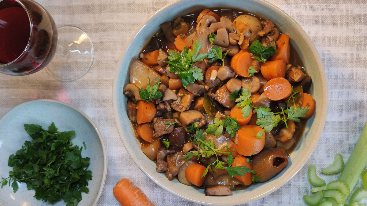 KI generiert: Das Bild zeigt eine Schüssel mit einem bunten Salat aus Rote-Bete-Scheiben, Karottenstreifen, Feldsalat, gehackten Nüssen und einem Klecks Sahne oder Joghurt in der Mitte. Der Salat liegt auf einem Holztisch.
