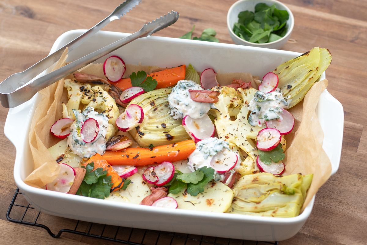 KI generiert: Das Bild zeigt eine Schüssel mit einem bunten Salat aus Rote-Bete-Scheiben, Karottenstreifen, Feldsalat, gehackten Nüssen und einem Klecks Sahne oder Joghurt in der Mitte. Der Salat liegt auf einem Holztisch.