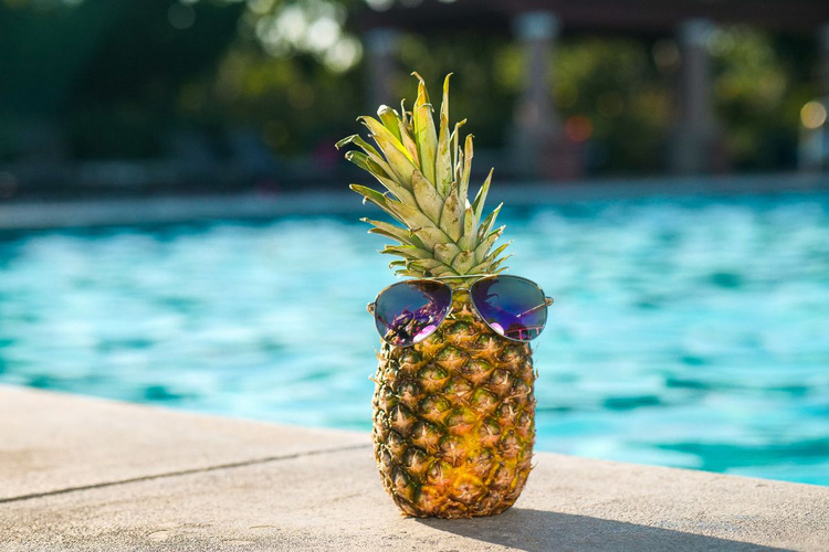 KI generiert: Eine Ananas mit Sonnenbrille steht am Rand eines Pools.