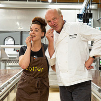 KI generiert: Zwei Personen in einer Schokoladenfabrik verkosten. Text auf Kleidung: "Zotter".