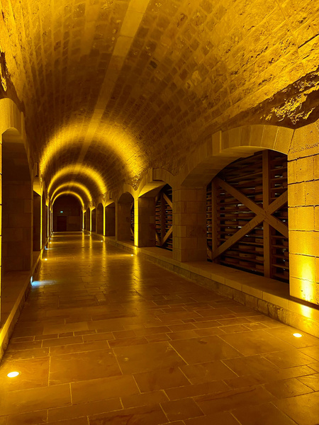 KI generiert: Beleuchteter, gewölbter Korridor mit Steinboden und Gelblichbraunen Steinen.