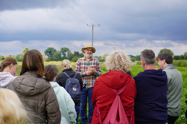KI generiert: Eine Gruppe von Menschen steht auf einem Feld, zentral ist eine Person mit Hut.