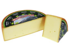 KI generiert: Ein runder Laib Käse, teils aufgeschnitten. Auf der Rinde: "Almradler Bio-Heumilchkäse".