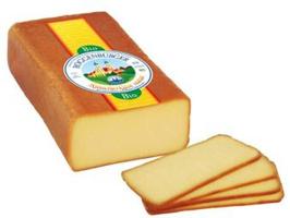 KI generiert: Ein Block Bio-Käse mit Etikett und mehrere Scheiben davon. Text: "Bio Bergbauernkäse".