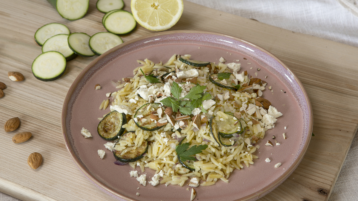 KI generiert: Das Bild zeigt eine Schüssel mit einem bunten Salat aus Rote-Bete-Scheiben, Karottenstreifen, Feldsalat, gehackten Nüssen und einem Klecks Sahne oder Joghurt in der Mitte. Der Salat liegt auf einem Holztisch.
