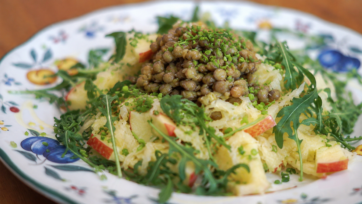 KI generiert: Das Bild zeigt eine Schüssel mit einem bunten Salat aus Rote-Bete-Scheiben, Karottenstreifen, Feldsalat, gehackten Nüssen und einem Klecks Sahne oder Joghurt in der Mitte. Der Salat liegt auf einem Holztisch.