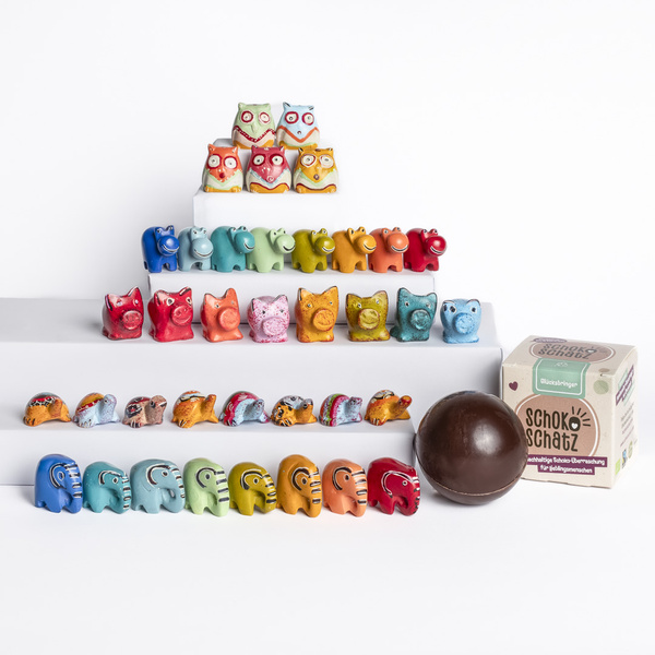 KI generiert: Bunte Tierfiguren aus Ton oder Keramik vor weißem Hintergrund. Text: "schoko schatz" auf einer Verpackung.