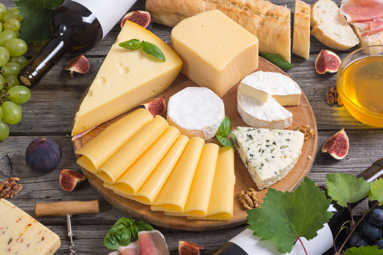 KI generiert: Eine Käseplatte mit verschiedenen Käsesorten, Baguette und Wein auf einem Holzbrett.