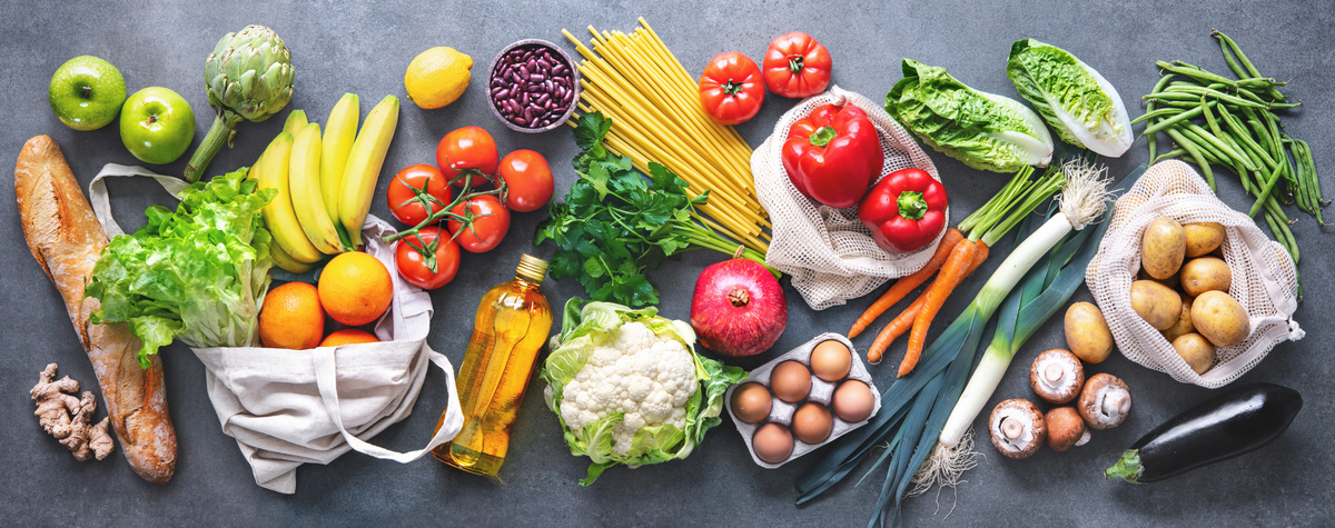 KI generiert: Verschiedene frische Lebensmittel wie Obst, Gemüse, Brot und Pasta sind auf einer grauen Oberfläche angeordnet.