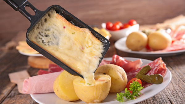 KI generiert: Käse schmilzt über Kartoffeln, Schinken und Essiggurken auf einem Teller.