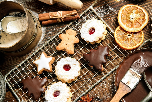 KI generiert: Verschiedene Weihnachtsplätzchen auf einem Gitter mit Zimtstangen, getrockneten Orangen und Schokolade.