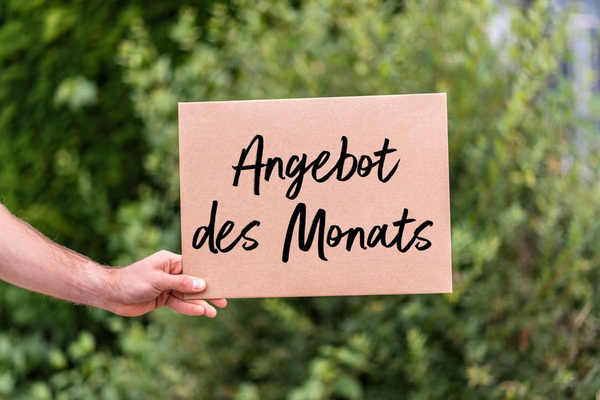 KI generiert: Das Bild zeigt zwei Personen in grüner Arbeitskleidung, die lächelnd eine Kiste mit frischem Obst und Gemüse halten. Im Hintergrund sind weitere Kisten mit Tomaten, Äpfeln und Salat zu sehen, was auf ein Lager oder eine Verkaufsstelle für frische Lebensmittel hinweist.