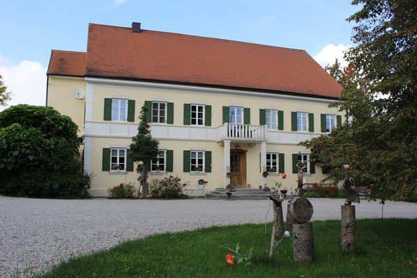 KI generiert: Ein großes, zweistöckiges Haus mit rotem Dach und grüner Umgebung.