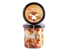 KI generiert: Das Bild zeigt ein Glas mit einem Lebensmittelprodukt namens "Wilde Weidekuh Carlo" in der Geschmacksrichtung "Curry & Dattel". Auf dem Etikett des Glases ist eine stilisierte Kuh abgebildet.