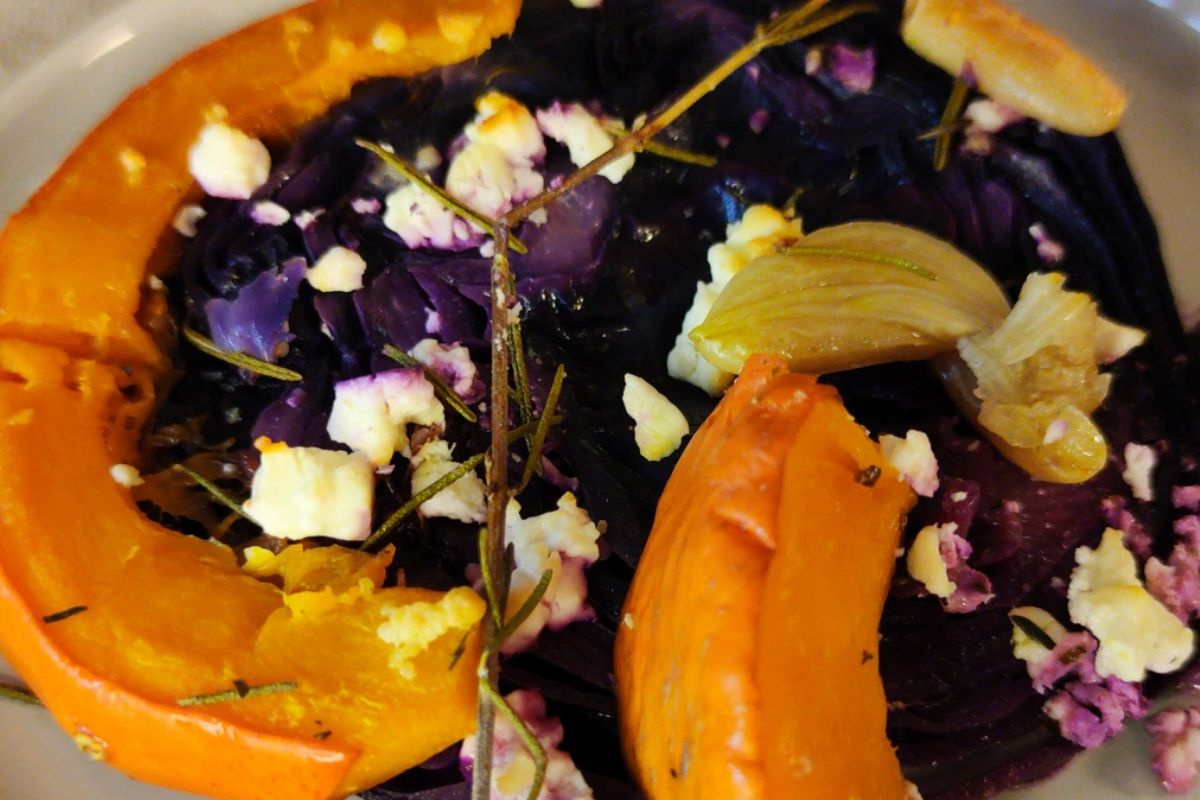 KI generiert: Das Bild zeigt eine Schüssel mit einem bunten Salat aus Rote-Bete-Scheiben, Karottenstreifen, Feldsalat, gehackten Nüssen und einem Klecks Sahne oder Joghurt in der Mitte. Der Salat liegt auf einem Holztisch.