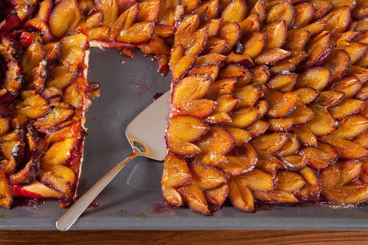 KI generiert: Pflaumenkuchen auf einem Blech, ein Stück wurde herausgeschnitten.