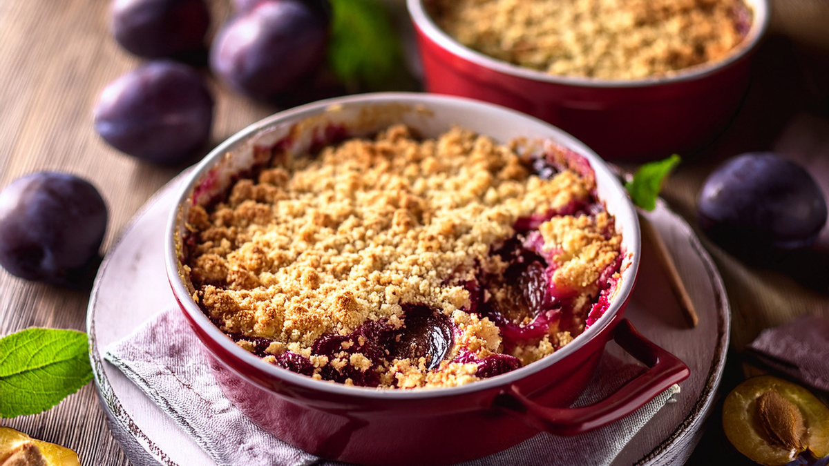 KI generiert: Das Bild zeigt eine Schüssel mit einem bunten Salat aus Rote-Bete-Scheiben, Karottenstreifen, Feldsalat, gehackten Nüssen und einem Klecks Sahne oder Joghurt in der Mitte. Der Salat liegt auf einem Holztisch.