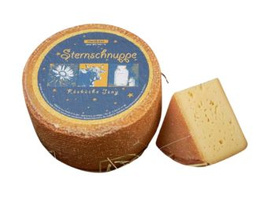 KI generiert: Ein runder Käselaib "Sternschnuppe" mit einem Stück abgeschnittenem Käse. Text: "Sternschnuppe".