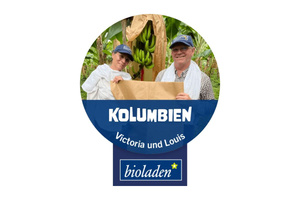 KI-generierte Beschreibung: Zwei Personen in einem Kaffeeanbaugebiet in Kolumbien. Text: "Kolumbien Victoria und Louis bioladen".
