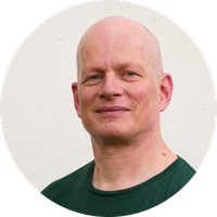 KI generiert: Ein lächelnder Mann mit Glatze vor einem neutralen Hintergrund.