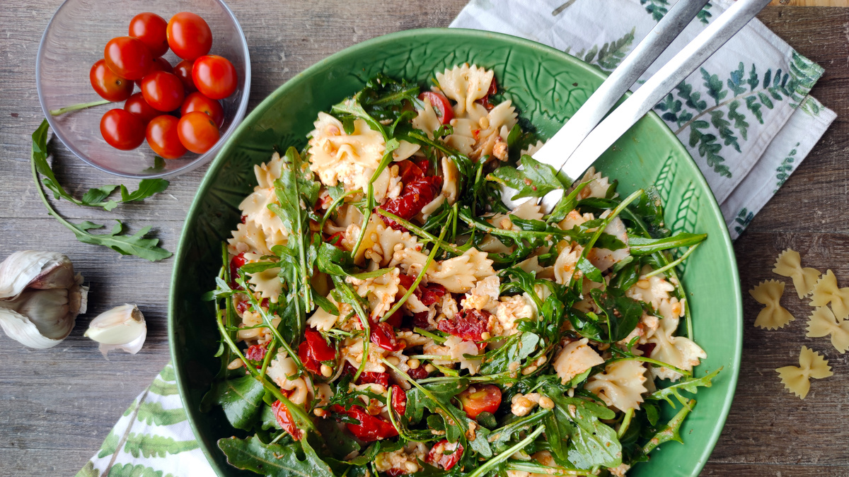 KI generiert: Das Bild zeigt eine Schüssel mit einem bunten Salat aus Rote-Bete-Scheiben, Karottenstreifen, Feldsalat, gehackten Nüssen und einem Klecks Sahne oder Joghurt in der Mitte. Der Salat liegt auf einem Holztisch.
