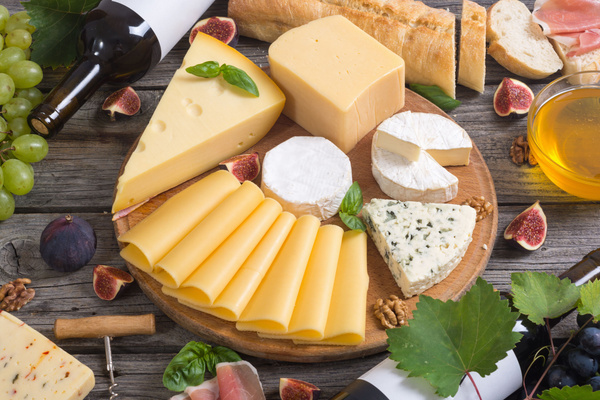 KI generiert: Das Bild zeigt zwei Personen in grüner Arbeitskleidung, die lächelnd eine Kiste mit frischem Obst und Gemüse halten. Im Hintergrund sind weitere Kisten mit Tomaten, Äpfeln und Salat zu sehen, was auf ein Lager oder eine Verkaufsstelle für frische Lebensmittel hinweist.