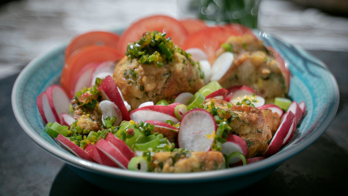KI generiert: Das Bild zeigt eine Schüssel mit einem bunten Salat aus Rote-Bete-Scheiben, Karottenstreifen, Feldsalat, gehackten Nüssen und einem Klecks Sahne oder Joghurt in der Mitte. Der Salat liegt auf einem Holztisch.