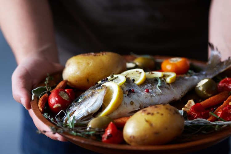 KI generiert: Ein Teller mit gebratenem Fisch, Kartoffeln und Gemüse wird serviert.
