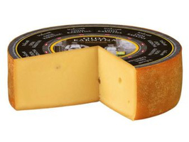 KI generiert: Ein runder Laib Käse mit Stück herausgeschnitten. Etikett oben drauf.